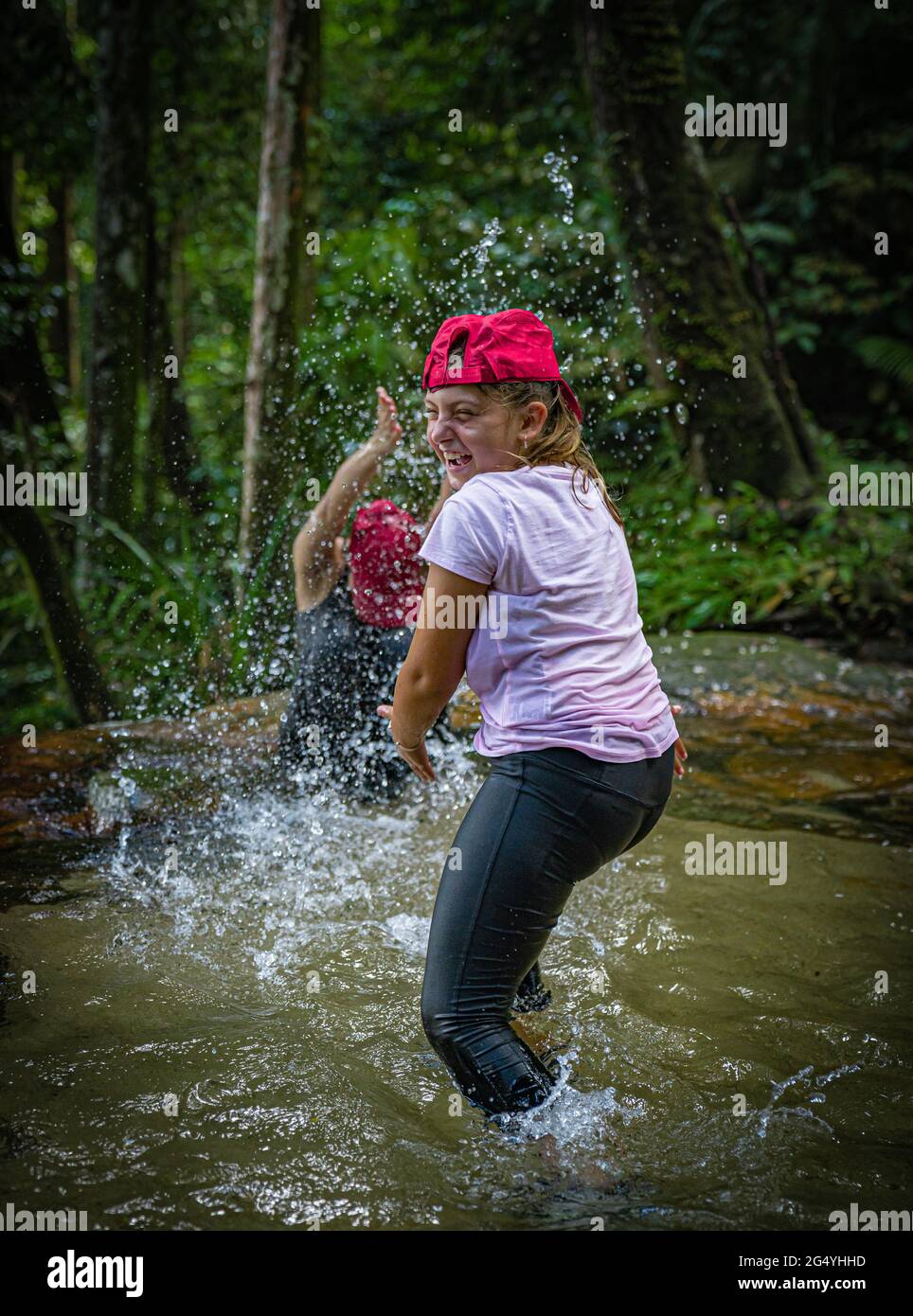 Zwei Mädchen, die sich im Regenwald in Malaysia mit Wasser bespritzen Stockfoto