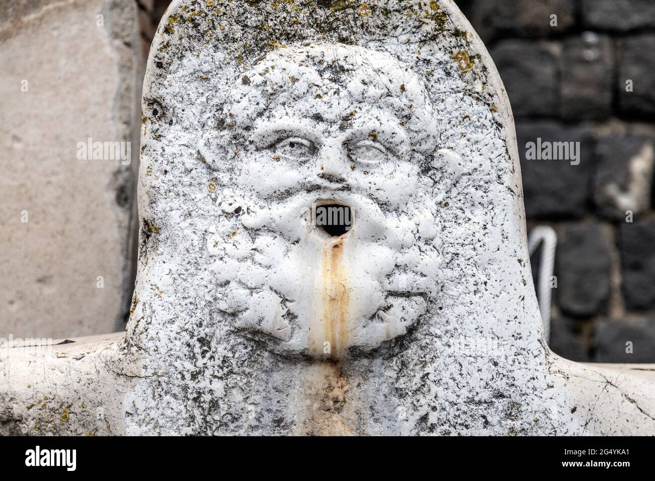 Detail eines geschnitzten Gesichtsreliefs auf einem Pferdetrog und Trinkbrunnen an der archäologischen Stätte der antiken Stadt Herculaneum, Kampanien, Italien Stockfoto