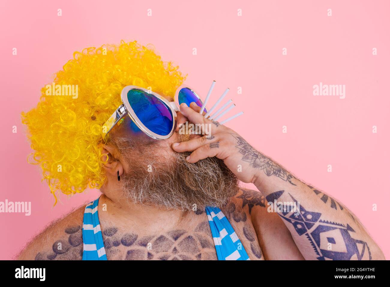 Fetter Mann mit Bart und Perücke raucht Zigaretten Stockfoto