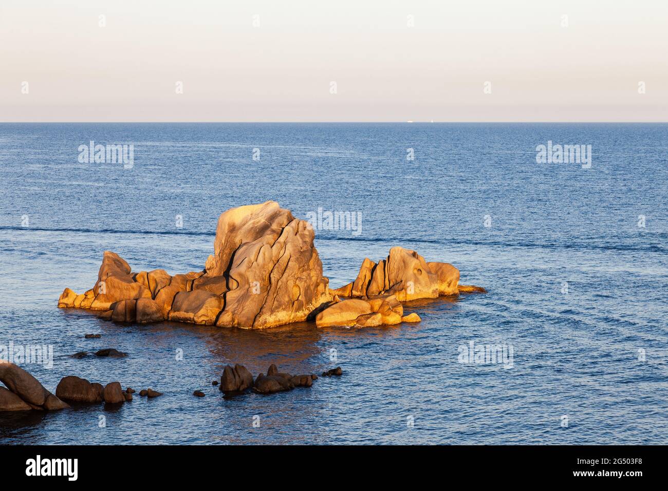Felsen im Meer, beleuchtet von der aufgehenden Sonne. Punkt von Campomoro. Korsika, Frankreich Stockfoto