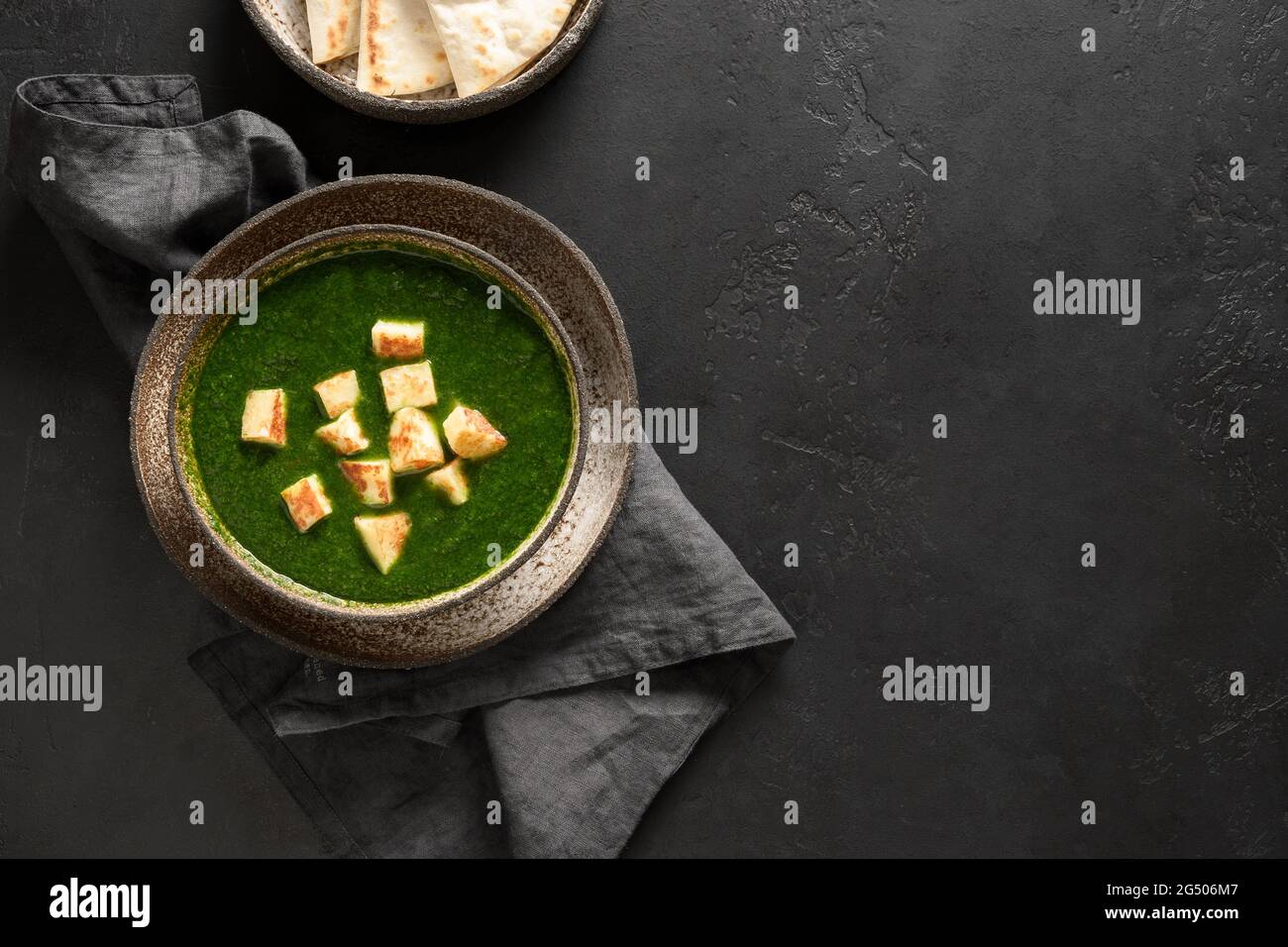 Palak Paneer von Spinat und Käse auf schwarzem Hintergrund mit Kopierraum. Traditionelle indische Küche. Blick von oben. Stockfoto