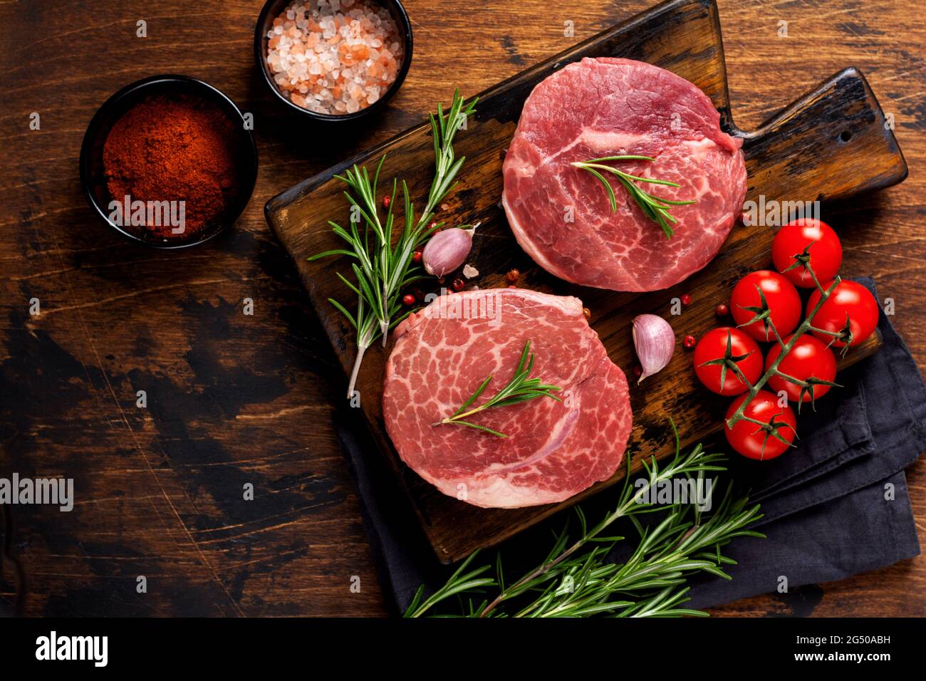 Zwei frische Parisienne rohes Steak auf Holzbrett mit Salz, Pfeffer und Rosmé in rustikalem Stil auf altem Holzhintergrund. Black angus. Draufsicht. Stockfoto