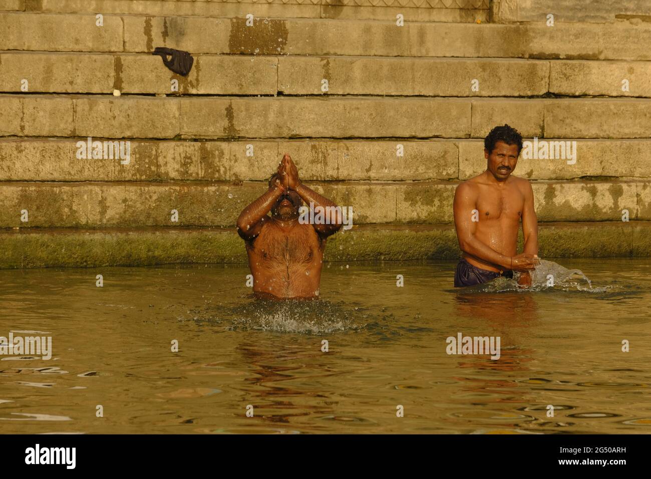 VARANASI, UTTAR PRADESH, INDIEN - FEBRUAR 02 2021: Indischer Mann, der am Ganges-Fluss in Varanasi, Uttar Pradesh, Indien, badet und Opfergaben macht Stockfoto