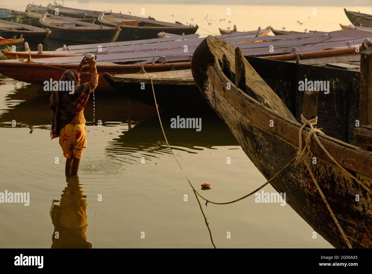 02. FEBRUAR 2021, VARANASI, UTTAR PRADESH, INDIEN - nicht identifizierte Frau, die im Fluss Ganga ein rituelles Bad nimmt und ein Ritual (Puja) im Fluss macht. Stockfoto