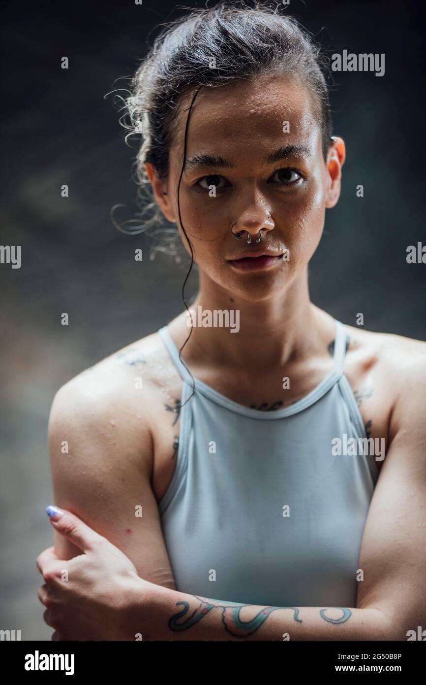 Porträt einer jungen Frau, die in einem Fitnessstudio auf die Kamera schaut. Sie trägt Sportkleidung und schwitzt nach einem Training. Stockfoto