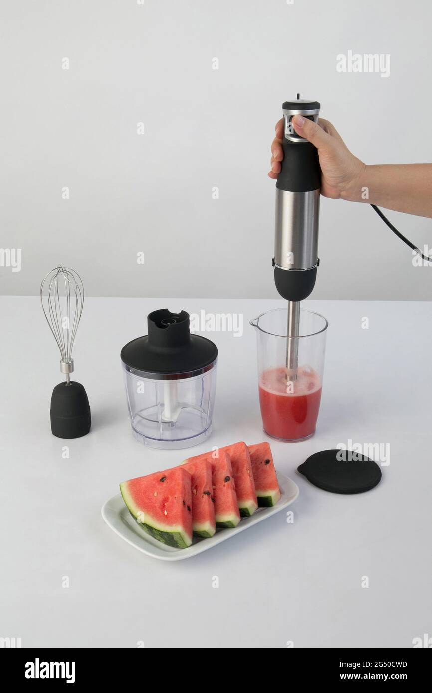 Wassermelone in einer Schüssel mit Stabmixer rühren. Elektrische Küchengeräte zur Herstellung von Säften, Saucen, Smoothies oder Maische von Fleisch und Gemüse Stockfoto