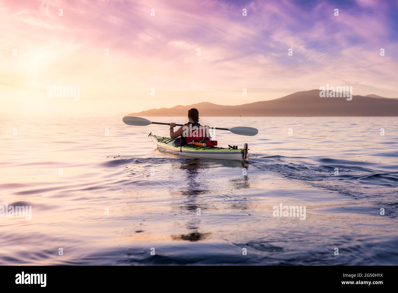Frau auf einem Seekajak paddelt im Meer. Stockfoto