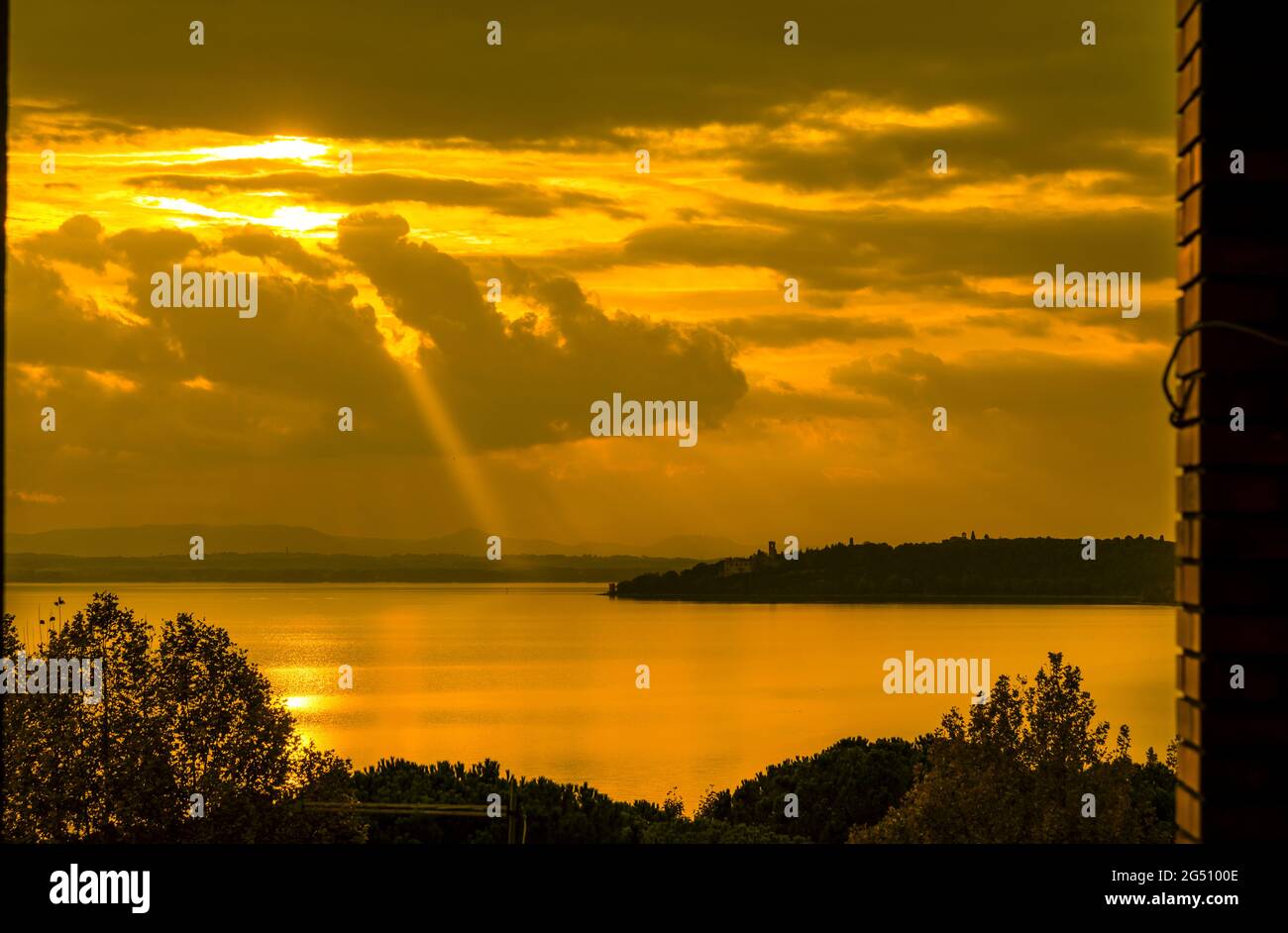Goldener Sonnenuntergang mit Sonnenstrahl über dem Trasimeno-See und der Isola Maggiore (Großinsel) in Umbrien Stockfoto