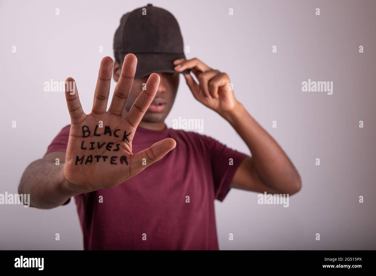 Nahaufnahme der Hand eines afrikanischen Mannes mit dem Zitat „Black Lives Matter“. Mann, der eine Mütze trägt, die seine Augen bedeckt. Verschwommener Hintergrund und Gesicht und Handfläche Stockfoto