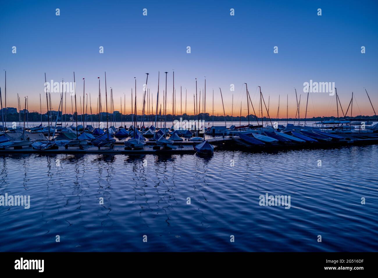 Überdachte Segelboote auf dem Wasser vor der Silhouette einer Stadt Stockfoto