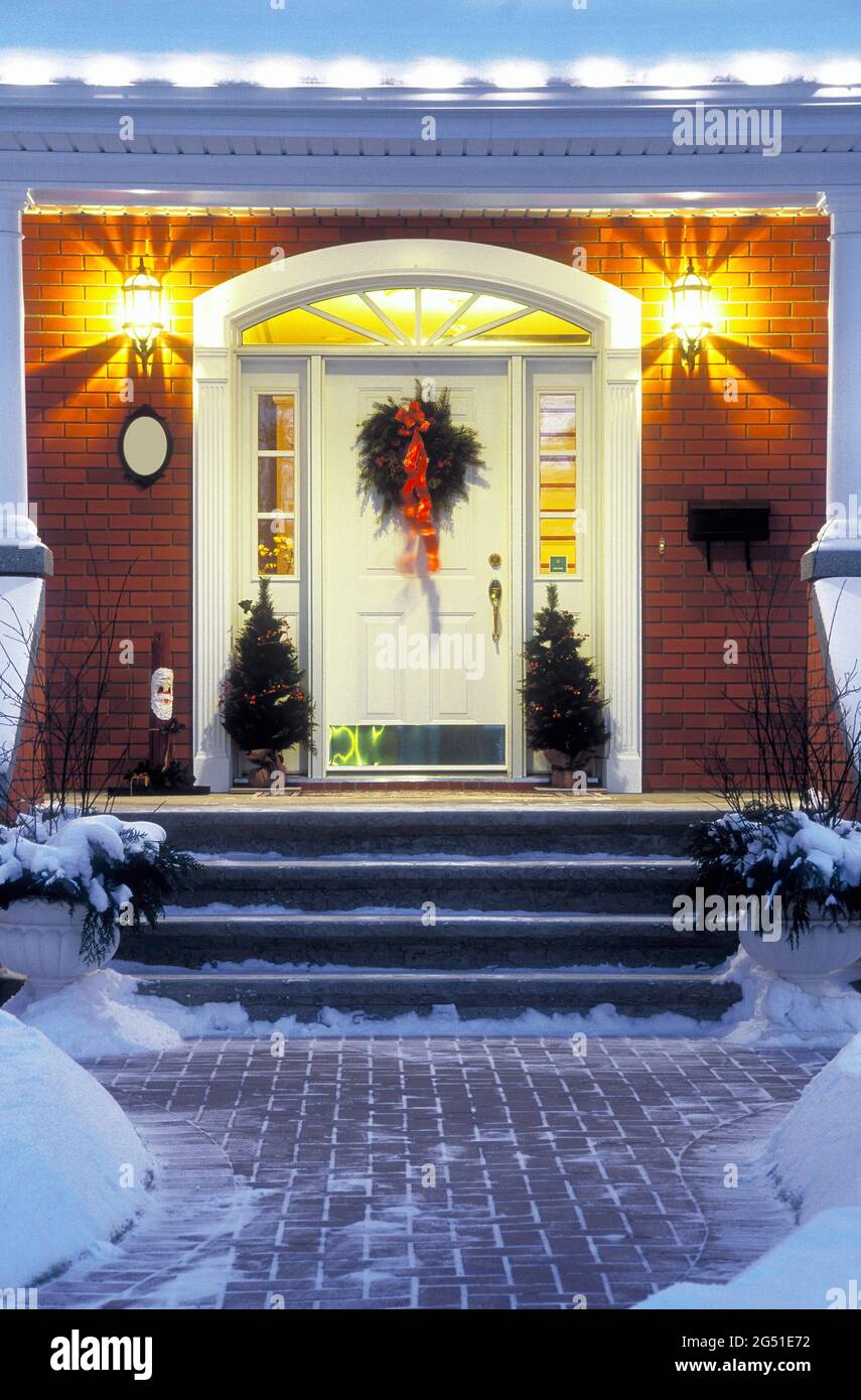Eingangstür und Veranda des Hauses mit Weihnachtsdekorationen am Abend Stockfoto