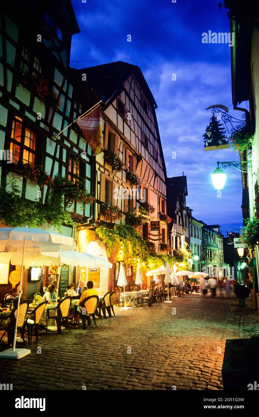 Straßen- und Straßencafés in der Altstadt bei Nacht, Riquewihr, Elsass, Frankreich Stockfoto