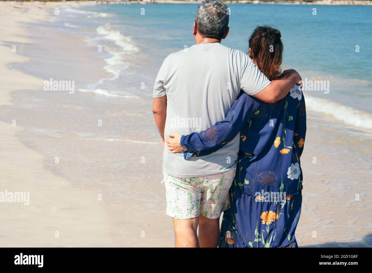 Ein älteres Latino-Paar, das vor sich am Strand läuft. Stockfoto