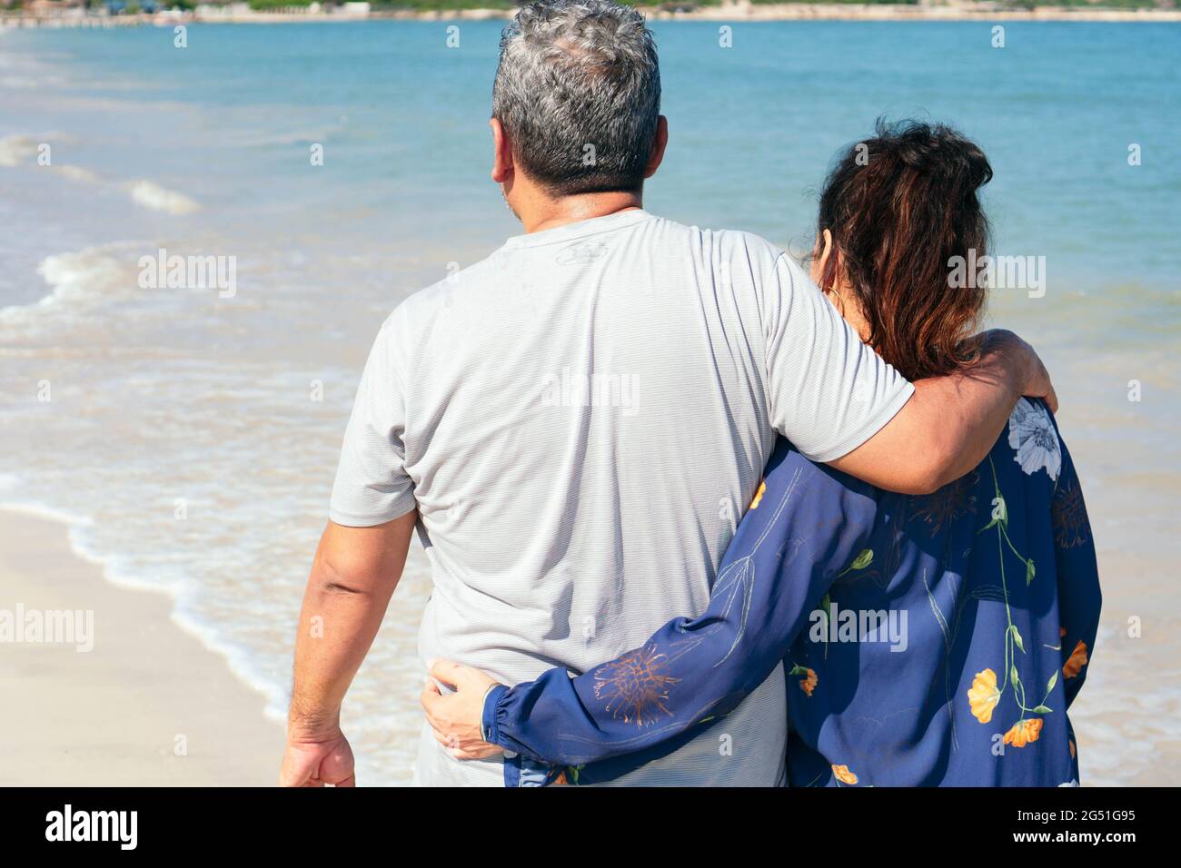 Ein älteres Paar, das vor ihnen am Strand spazieren ging. Stockfoto