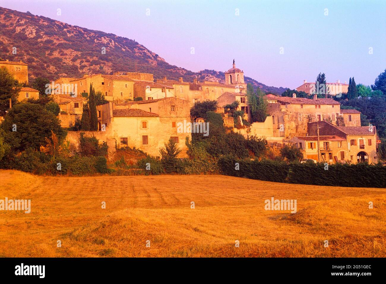 Feld und Häuser im Dorf bei Sonnenuntergang, Baubec, Provence, Frankreich Stockfoto