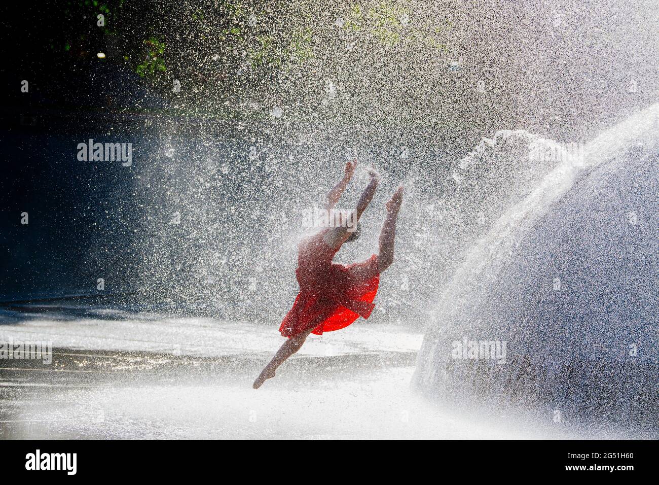 Frau in rotem Kleid, die gegen den Brunnen tanzt Stockfoto