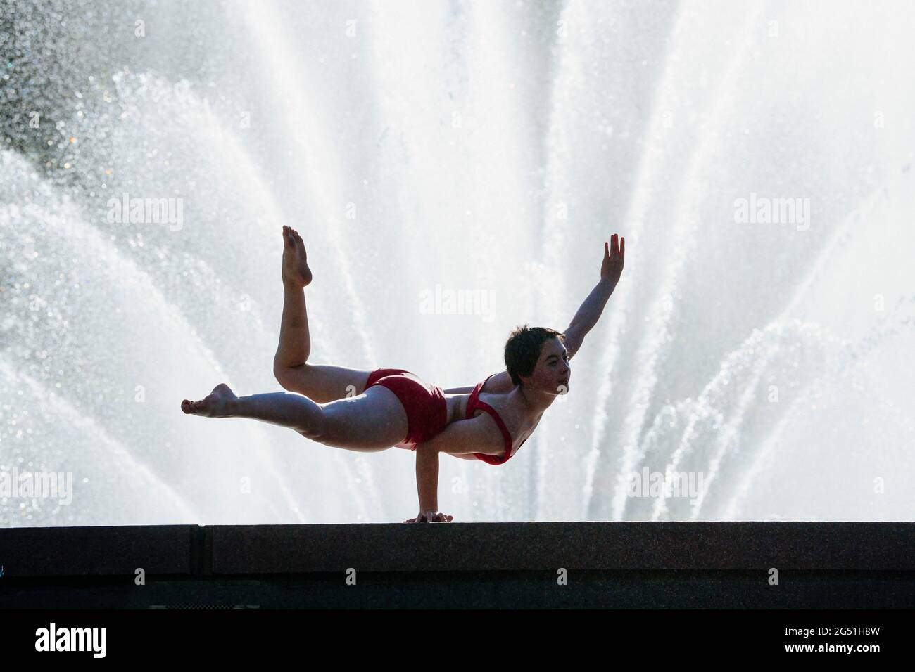 Frau mit akrobatischem Handstand stellt sich gegen den Brunnen Stockfoto