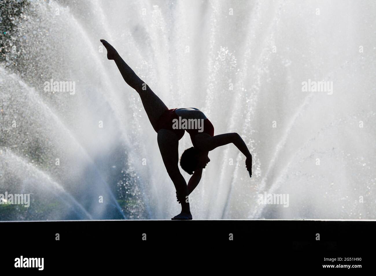 Frau, die akrobatische Pose gegen den Brunnen macht Stockfoto