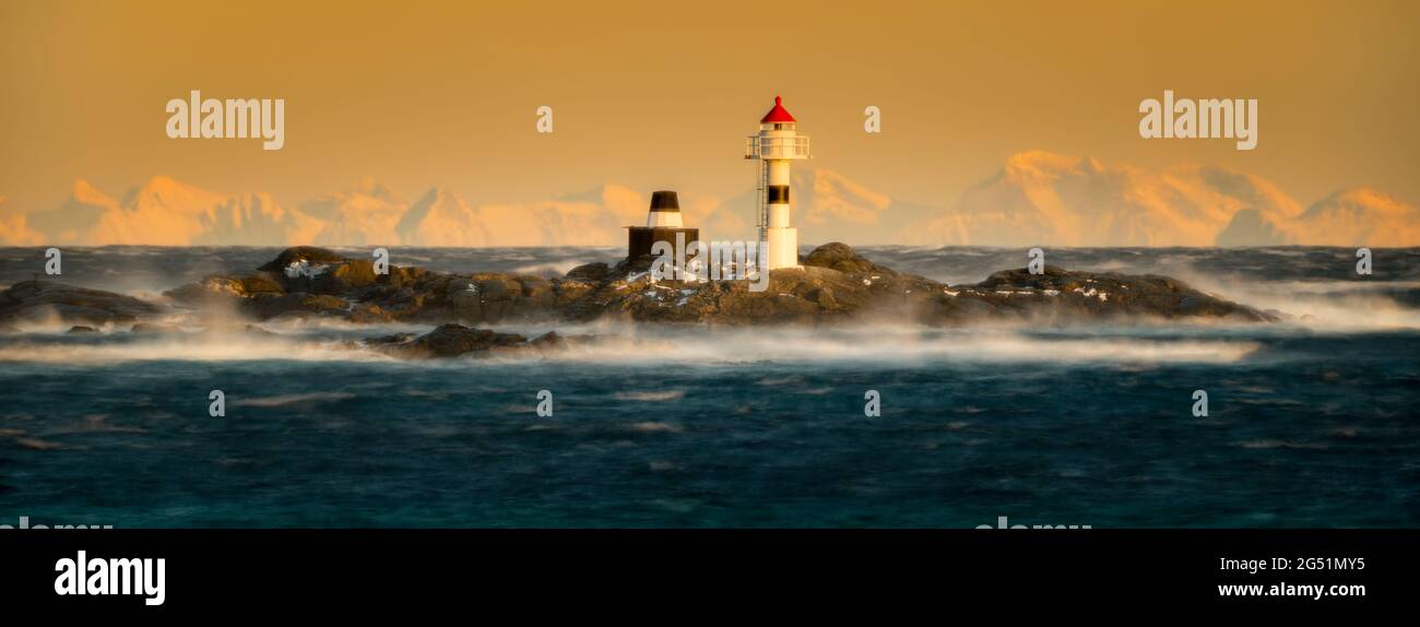 Insel mit Leuchtturm im Meer bei Sonnenuntergang, Vaeroya, Lofoten, Norwegen Stockfoto