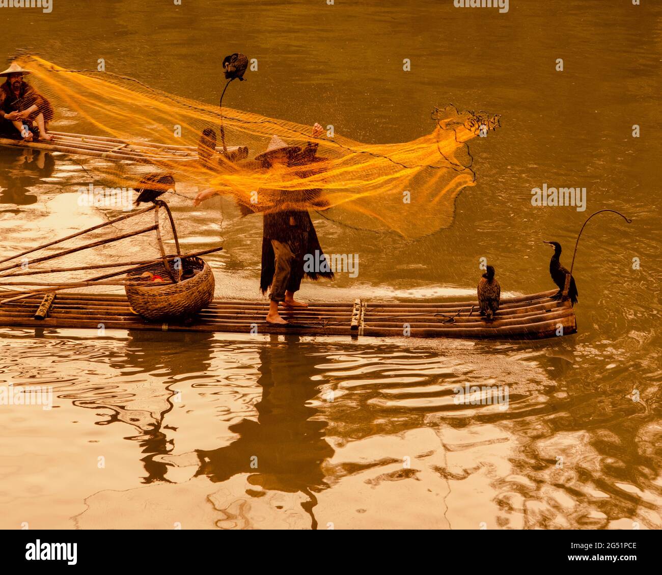 Kormoran-Fischer wirft bei Sonnenuntergang Netz, Li River, Xingping, Provinz Shaanxi, China Stockfoto