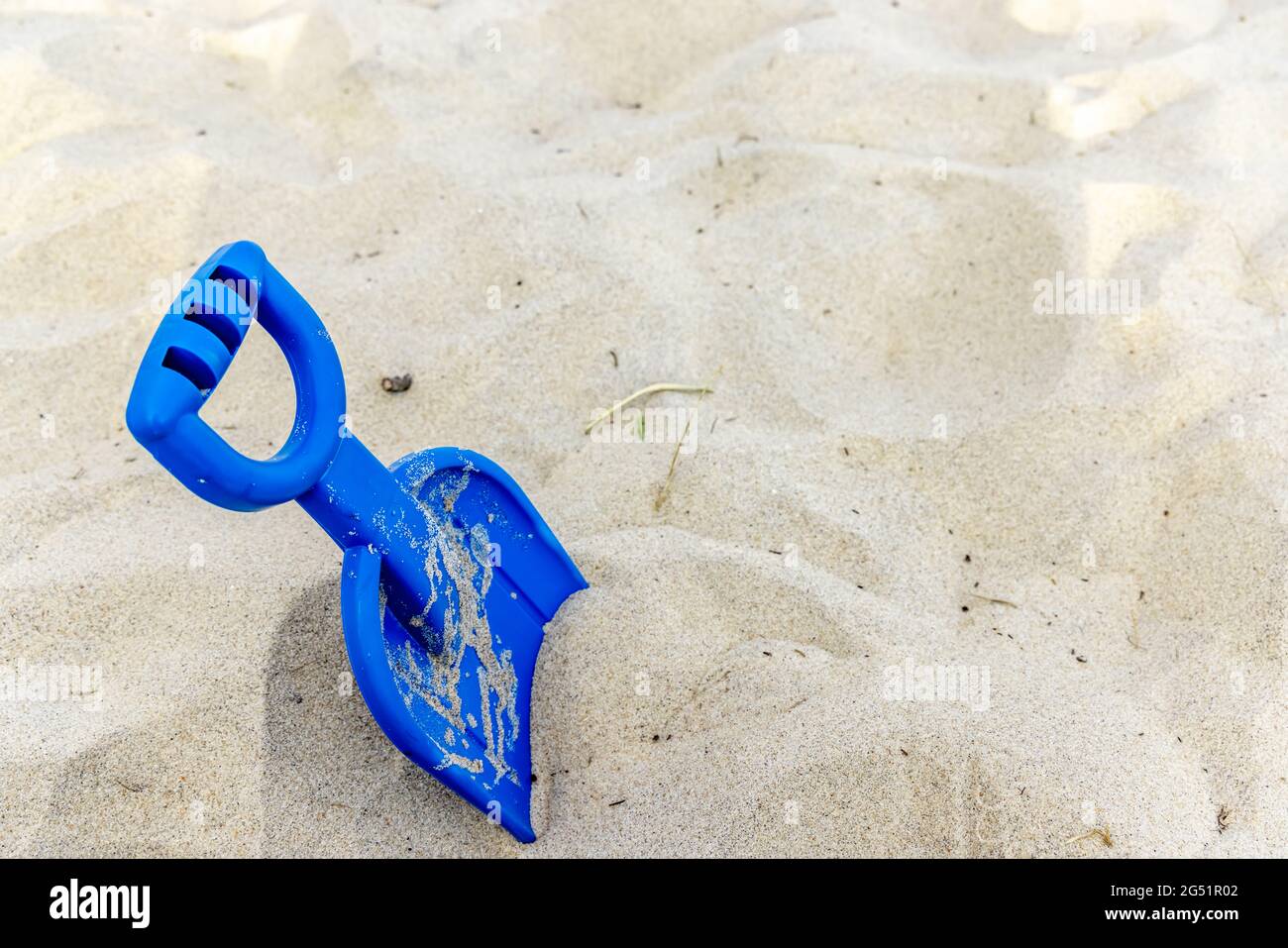 Eine blaue Plastikschaufel für Kinder im Sand Stockfoto