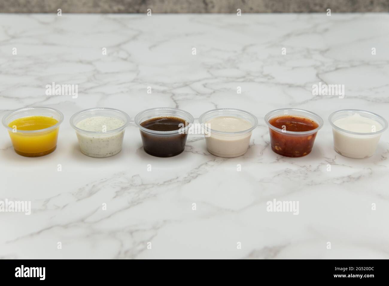 Verschiedene kleine Tassen mit verschiedenen Geschmacksrichtungen von Dipping-Saucen für Ihre mediterrane Mahlzeit. Stockfoto