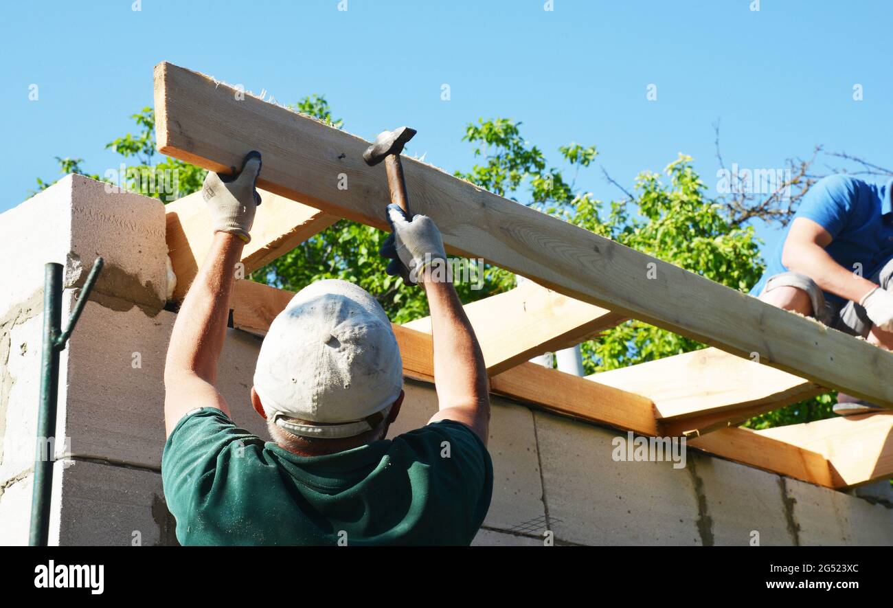 Dachkonstruktion. Dachdecker sind Holzrahmen das Dach Installation Dachsparren und Bretter mit Hämmern und Nägeln. Stockfoto