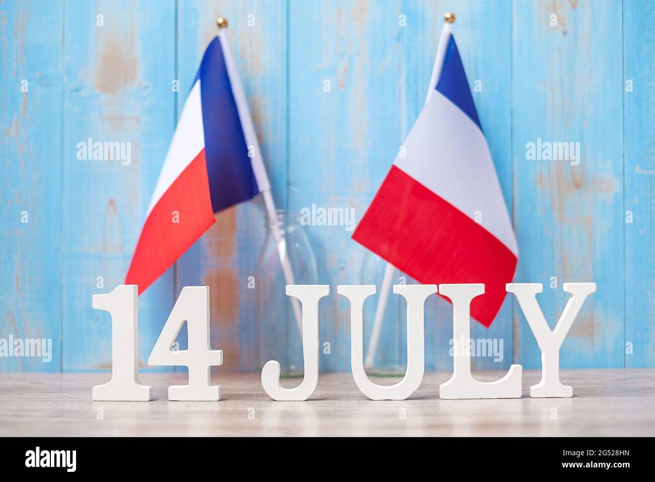 Holzkalender vom 14. Juli mit Miniatur-Frankreich-Fahnen. Französischer Nationalfeiertag, Bastille-Tag und Happy-Party-Konzepte Stockfoto