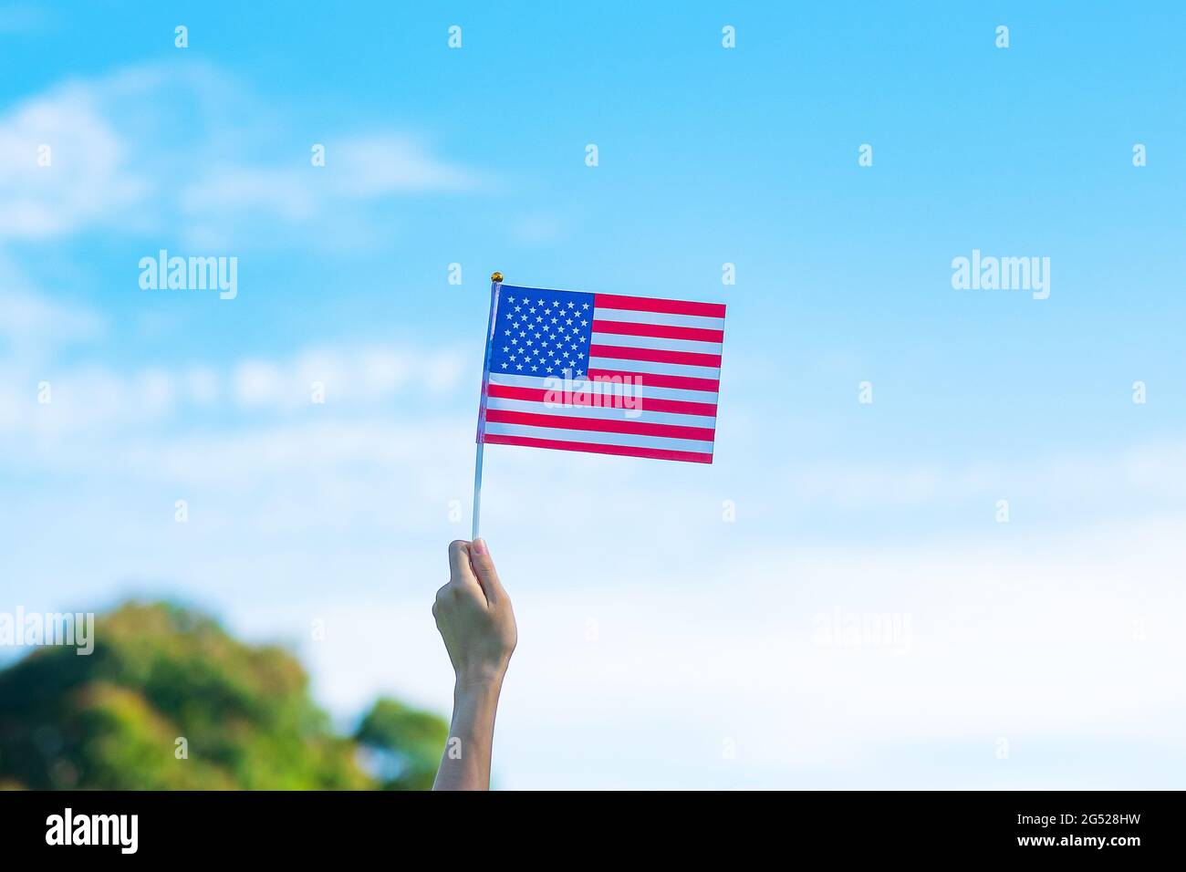 Hand hält die Flagge der Vereinigten Staaten von Amerika auf blauem Himmel Hintergrund. USA: Feiertag der Veteranen, Gedenkstätte, Unabhängigkeit (4. Juli) und Labor Day con Stockfoto