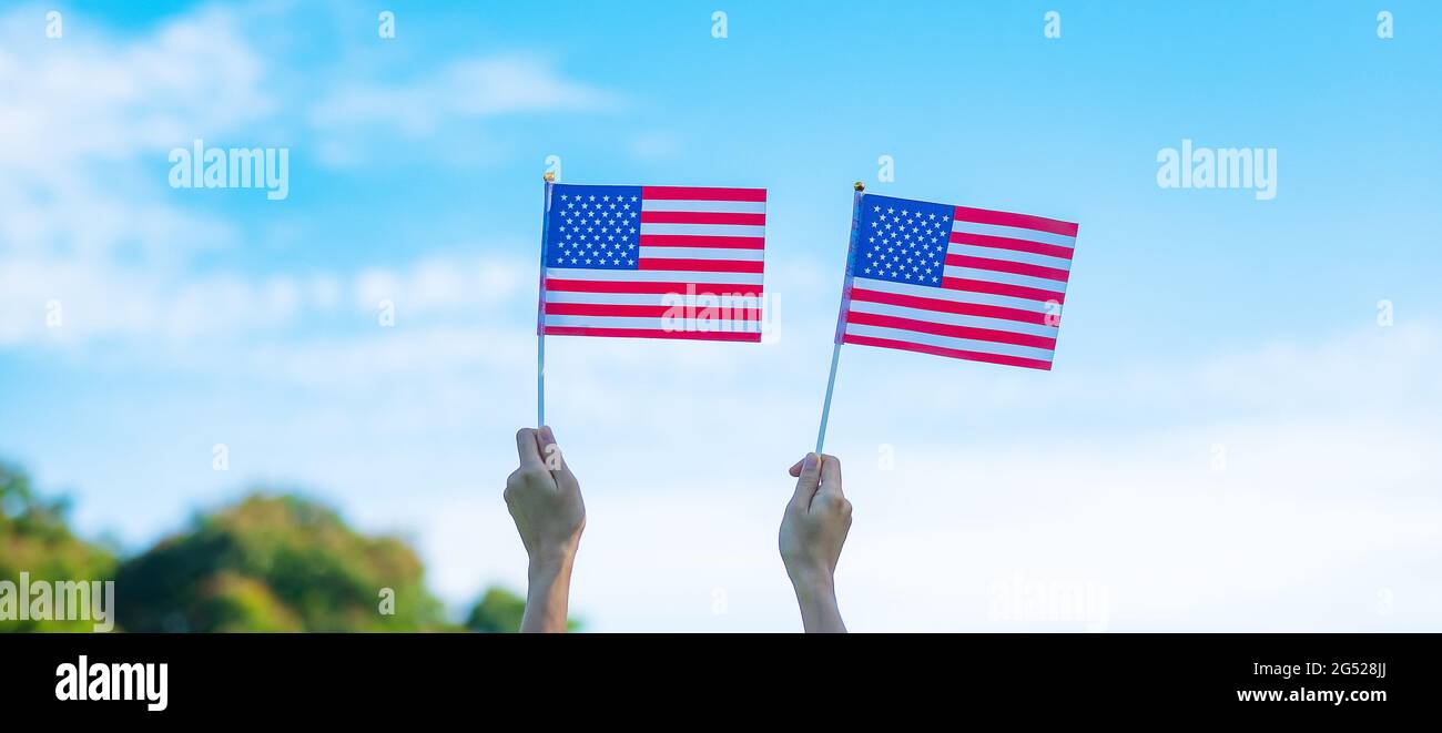 Hand hält die Flagge der Vereinigten Staaten von Amerika auf blauem Himmel Hintergrund. USA: Feiertag der Veteranen, Gedenkstätte, Unabhängigkeit (4. Juli) und Labor Day con Stockfoto