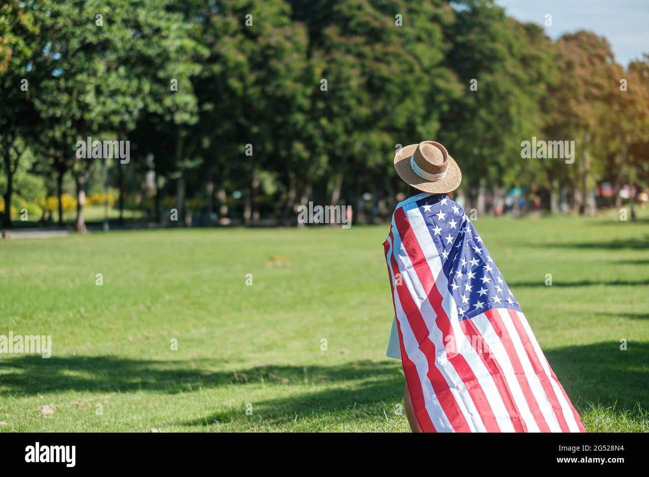 Frau, die mit der Flagge der Vereinigten Staaten von Amerika im Park im Freien reist. USA: Feiertag der Veteranen, Gedenkstätte, Unabhängigkeit (4. Juli) und Tag der Arbeit CO Stockfoto