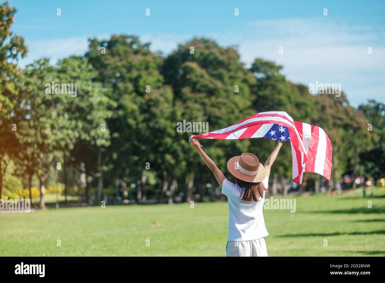 Frau, die mit der Flagge der Vereinigten Staaten von Amerika im Park im Freien reist. USA: Feiertag der Veteranen, Gedenkstätte, Unabhängigkeit (4. Juli) und Tag der Arbeit CO Stockfoto