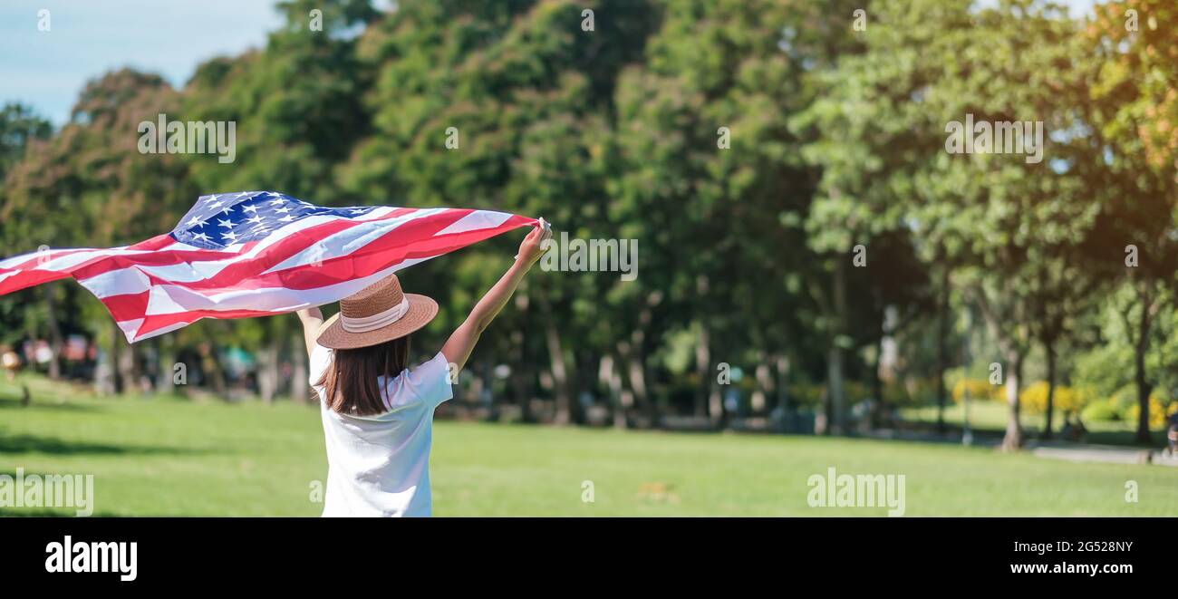 Frau, die mit der Flagge der Vereinigten Staaten von Amerika im Park im Freien reist. USA: Feiertag der Veteranen, Gedenkstätte, Unabhängigkeit (4. Juli) und Tag der Arbeit CO Stockfoto