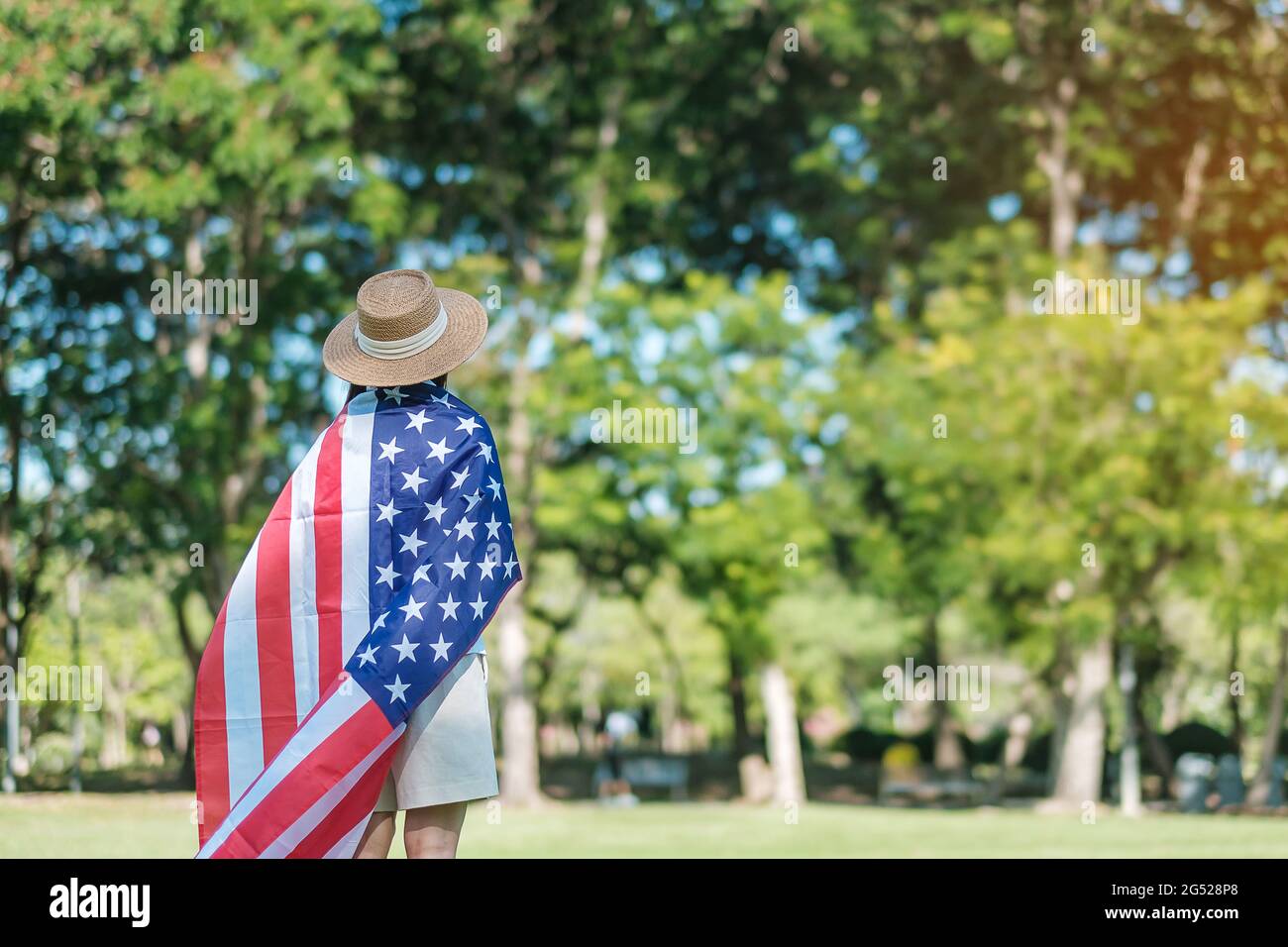 Frau, die mit der Flagge der Vereinigten Staaten von Amerika im Park im Freien reist. USA: Feiertag der Veteranen, Gedenkstätte, Unabhängigkeit (4. Juli) und Tag der Arbeit CO Stockfoto