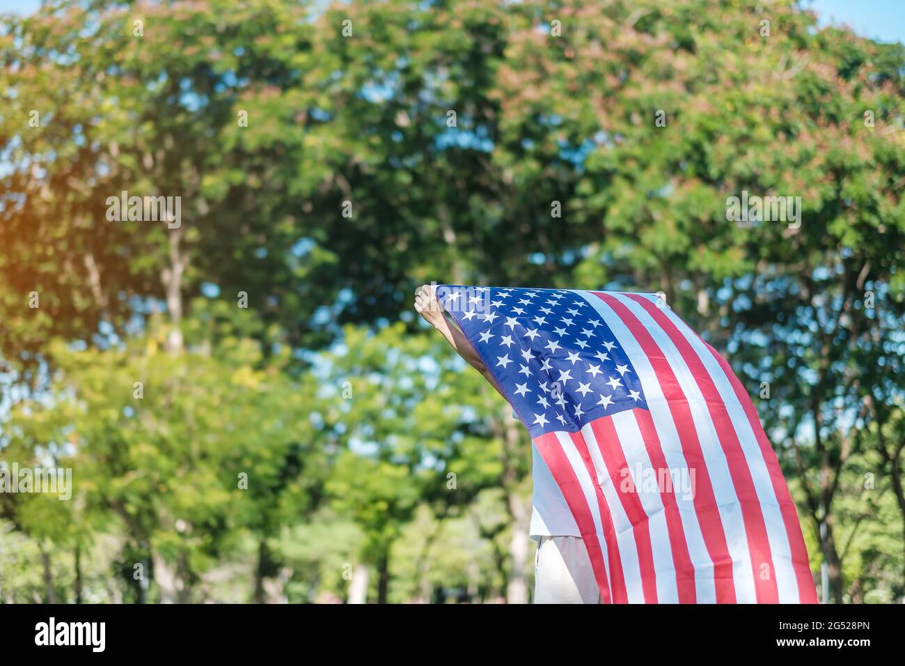Frau, die mit der Flagge der Vereinigten Staaten von Amerika im Park im Freien reist. USA: Feiertag der Veteranen, Gedenkstätte, Unabhängigkeit (4. Juli) und Tag der Arbeit CO Stockfoto