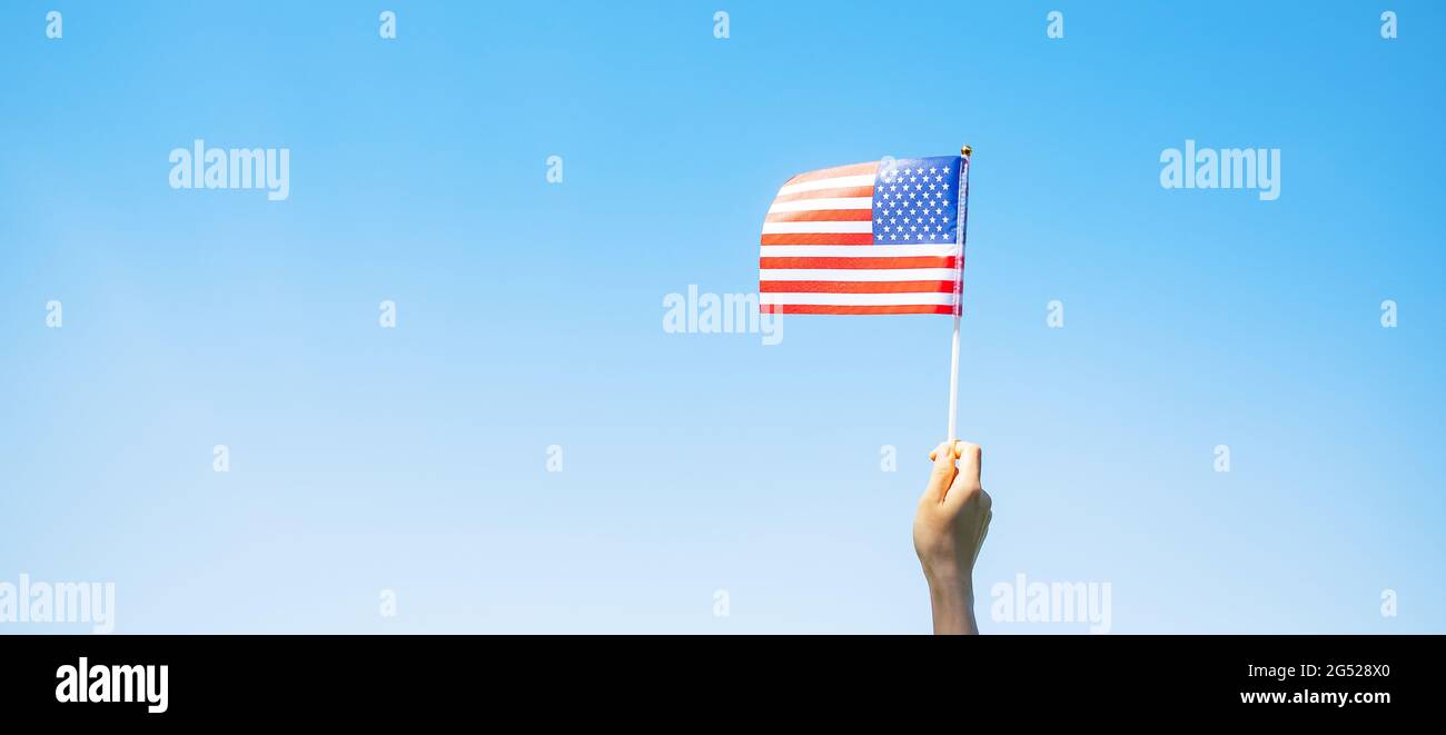 Hand hält die Flagge der Vereinigten Staaten von Amerika auf blauem Himmel Hintergrund. USA: Feiertag der Veteranen, Gedenkstätte, Unabhängigkeit (4. Juli) und Labor Day con Stockfoto