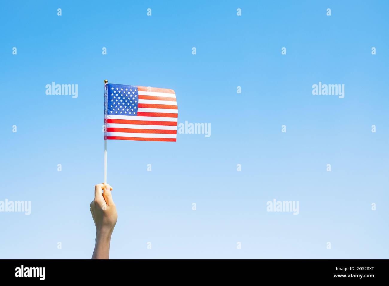 Hand hält die Flagge der Vereinigten Staaten von Amerika auf blauem Himmel Hintergrund. USA: Feiertag der Veteranen, Gedenkstätte, Unabhängigkeit (4. Juli) und Labor Day con Stockfoto