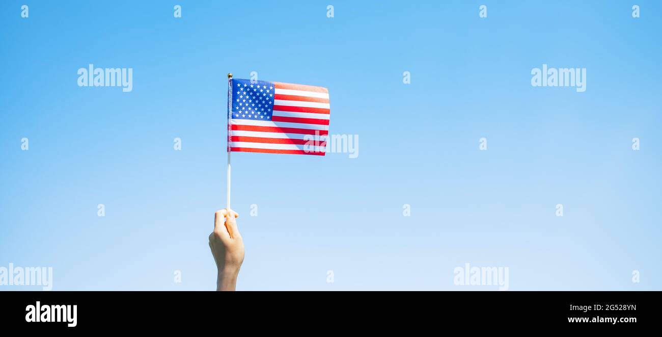 Hand hält die Flagge der Vereinigten Staaten von Amerika auf blauem Himmel Hintergrund. USA: Feiertag der Veteranen, Gedenkstätte, Unabhängigkeit (4. Juli) und Labor Day con Stockfoto