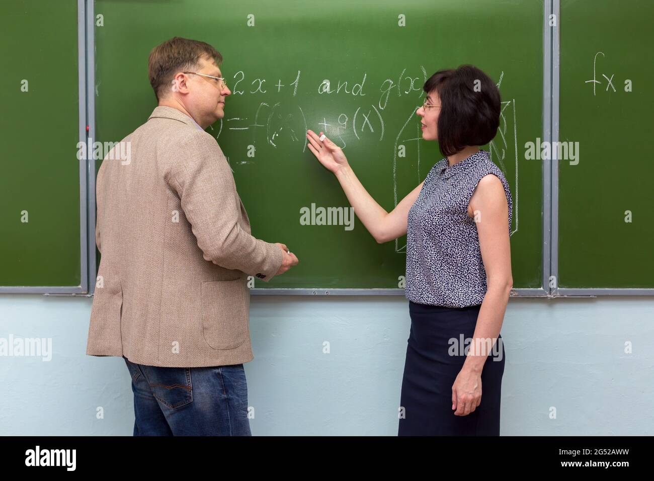 Ein Schüler erklärt dem Lehrer die Lösung des Problems an der Tafel. Stockfoto
