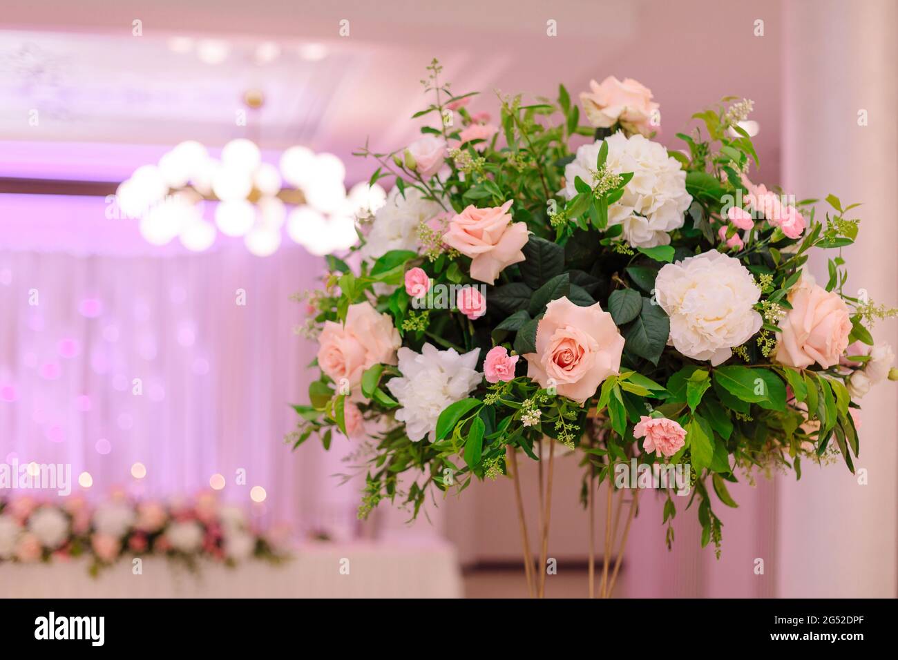 Elegantes, zentral geblümtes Hochzeitsarrangement im Vordergrund. Konzept von Hochzeitsveranstaltungen. Hochzeitsplaner. Luxus und Schönheit. Wichtige Lebensereignisse. Leben Stockfoto