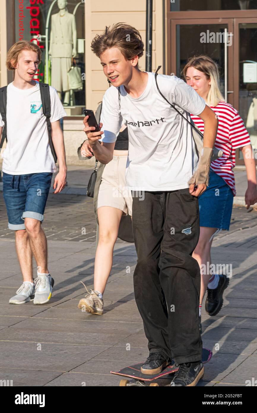 Junge oder Teenager Skateboarding in der Stadt und mit Smartphone, vertikal Stockfoto