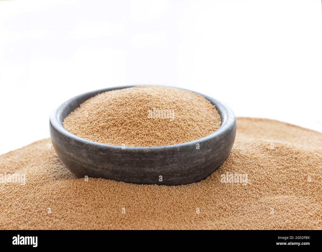 Amaranth hat gesundheitliche Vorteile, die reich an Proteinen, Ballaststoffen, Mikronährstoffen und Antioxidantien sind. Makrobild von Getreide in einer Schüssel auf weißem Hintergrund mit einem Stapel Stockfoto