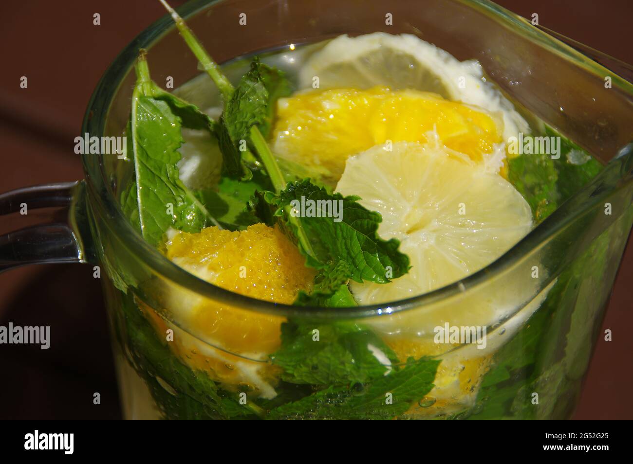 Ein kaltes Zitronengetränk in einem Glaskrug. Frische, frisch zubereitete Limonade. Bio-Minzgetränk mit Zitrusscheiben. Stockfoto