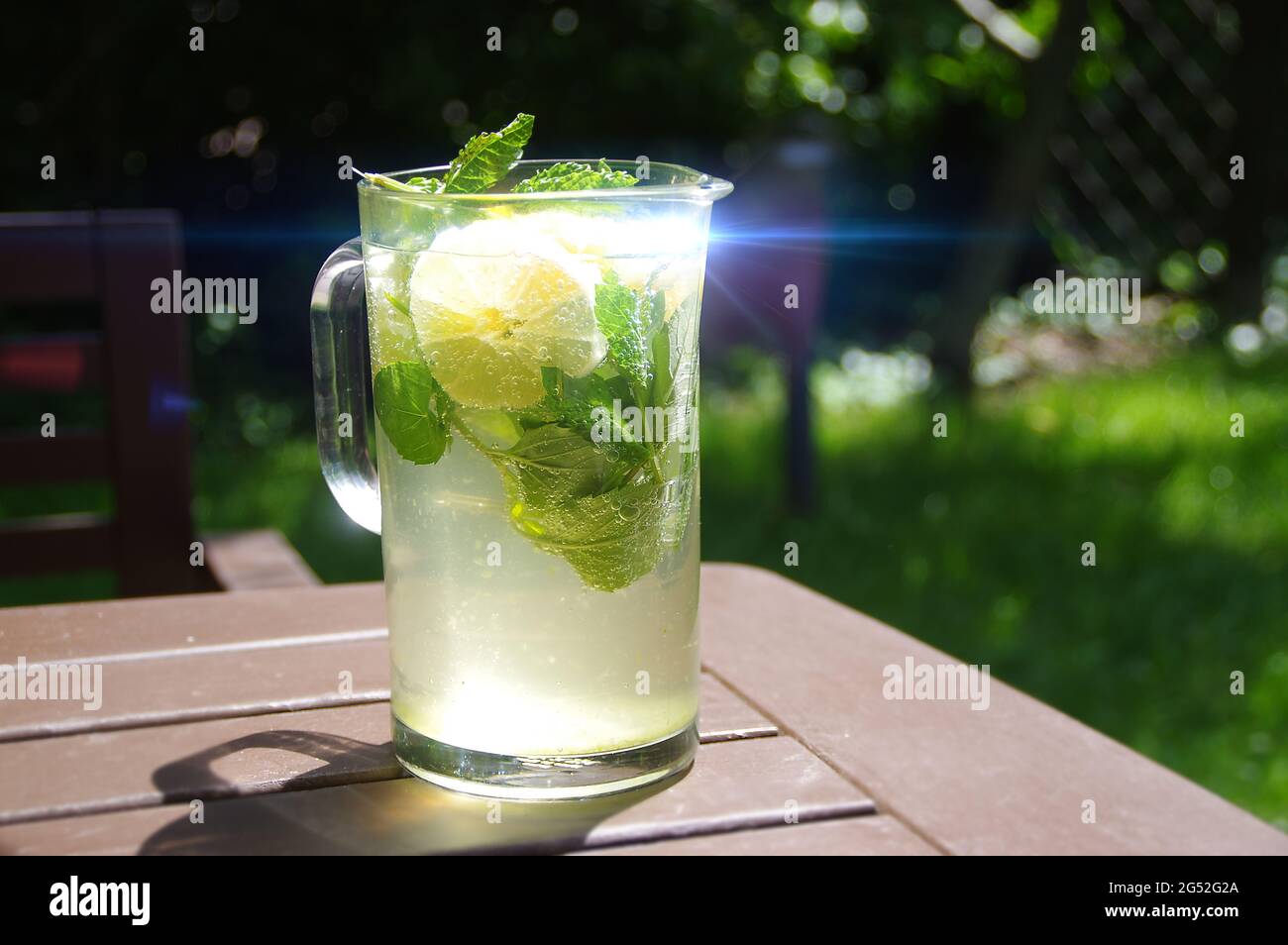 Ein kaltes Zitronengetränk in einem Glaskrug. Frische, frisch zubereitete Limonade. Bio-Minzgetränk mit Zitrusscheiben. Stockfoto