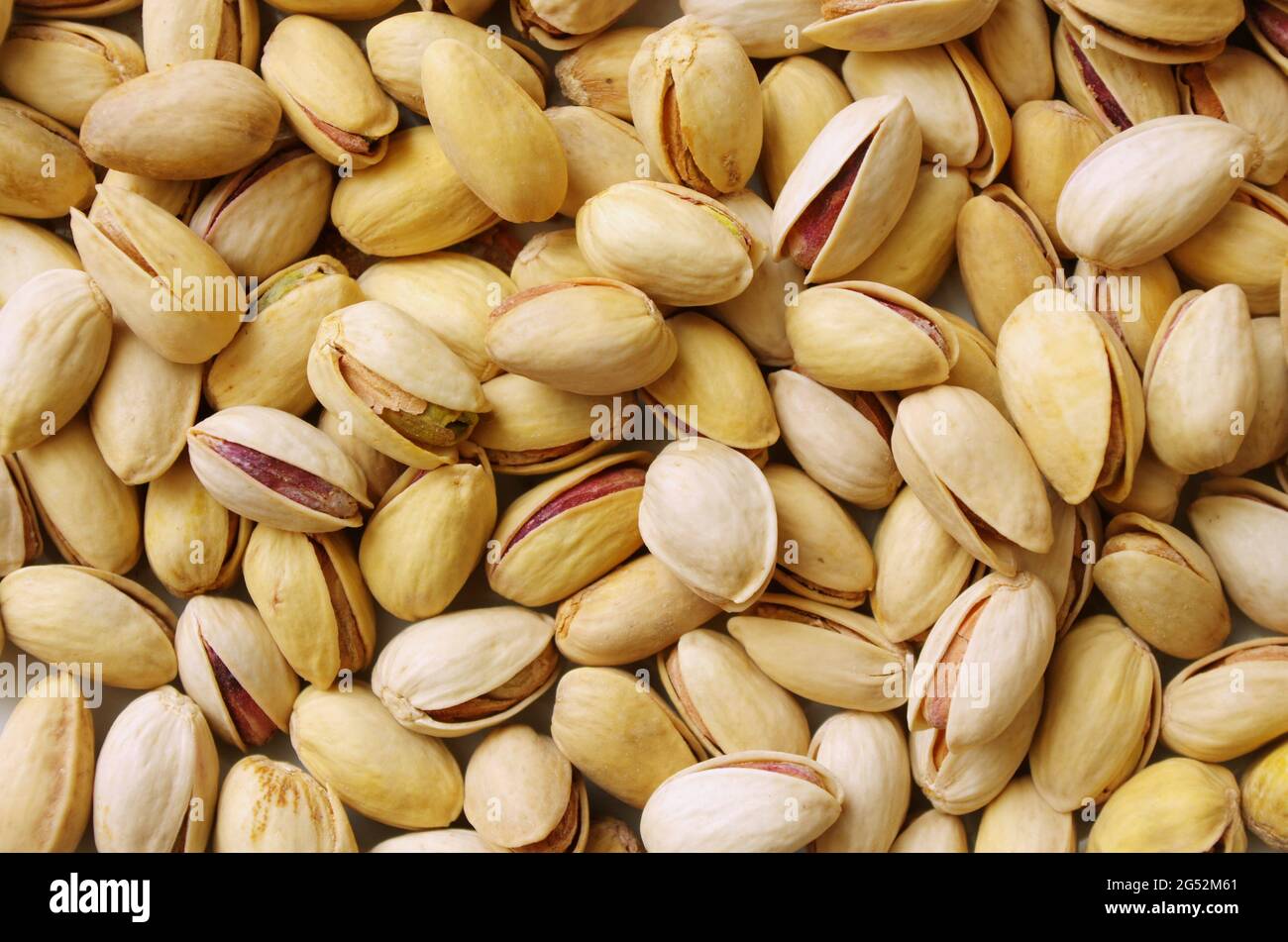 Haufen Pistazien in der Schale aus nächster Nähe. Pistazien gesunde Omega-3-Fettsäure. Leckere Pistazien als Hintergrundtextur, flach liegend. Gesunde Lebensmittel, Snack. Stockfoto