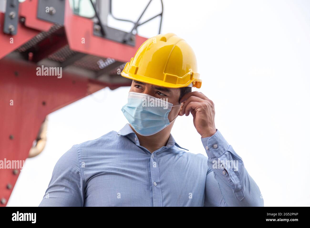 Junger Geschäftsmann, der Gesichtsmaske trägt, um Coronavirus oder Covid-19-Pandemie und pm2,5-Luftverschmutzung durch Verkehr und produzierende Industrie zu schützen Stockfoto