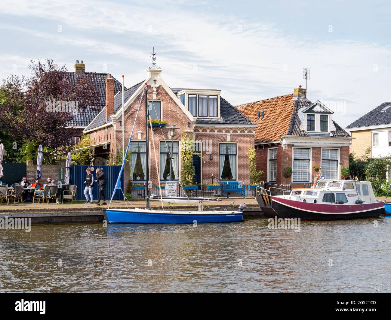 Boote und Häuser am Kai des EE-Kanals im Dorf Woudsend in Friesland, Niederlande Stockfoto