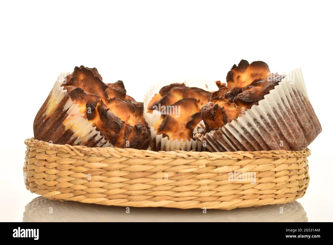 Drei duftende Schokoladenkuhmuffins in einem Strohteller, Nahaufnahme, isoliert auf Weiß. Stockfoto