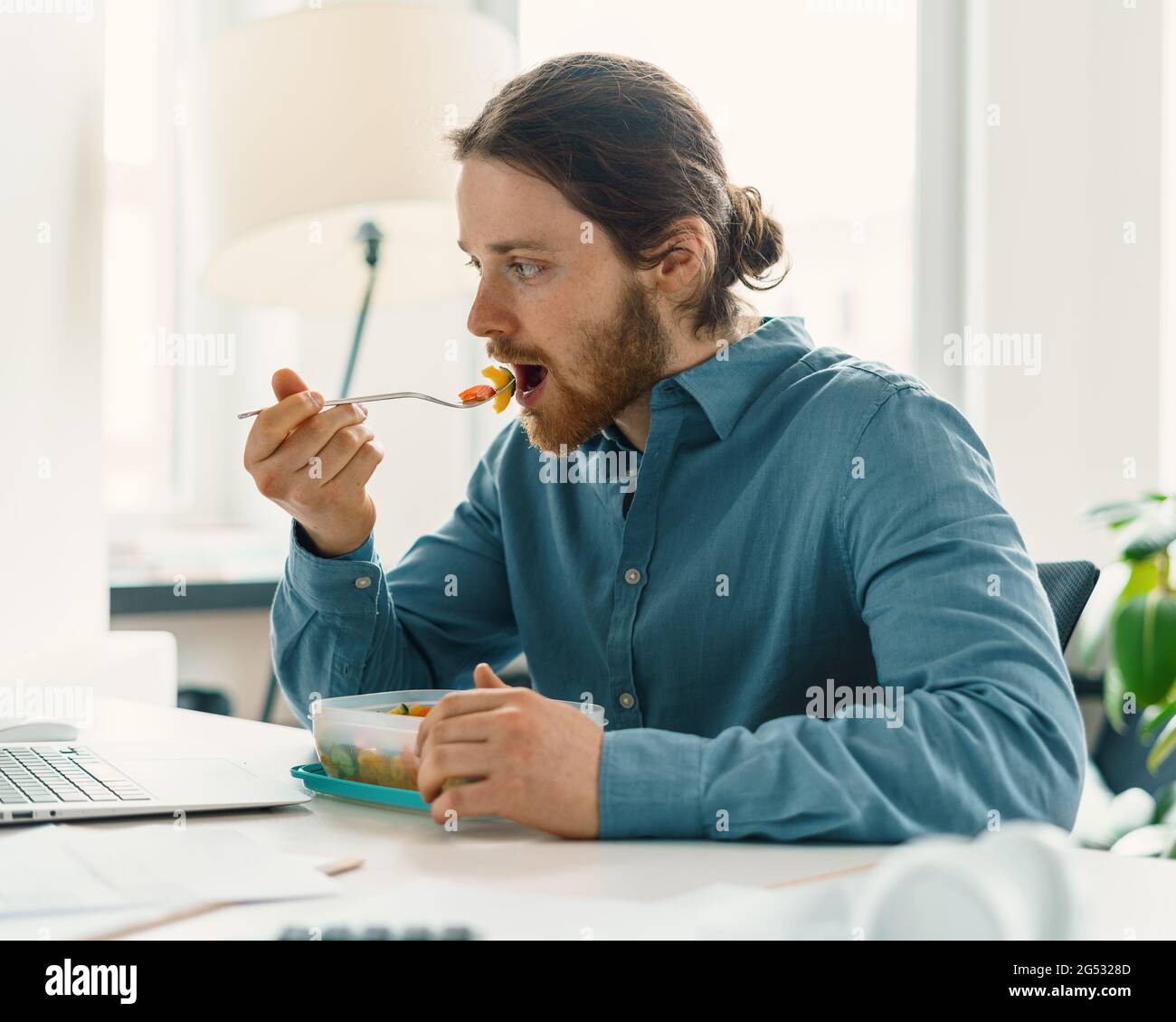 Hungriger Mann, der während der Mittagspause vegan gegessen hat Stockfoto