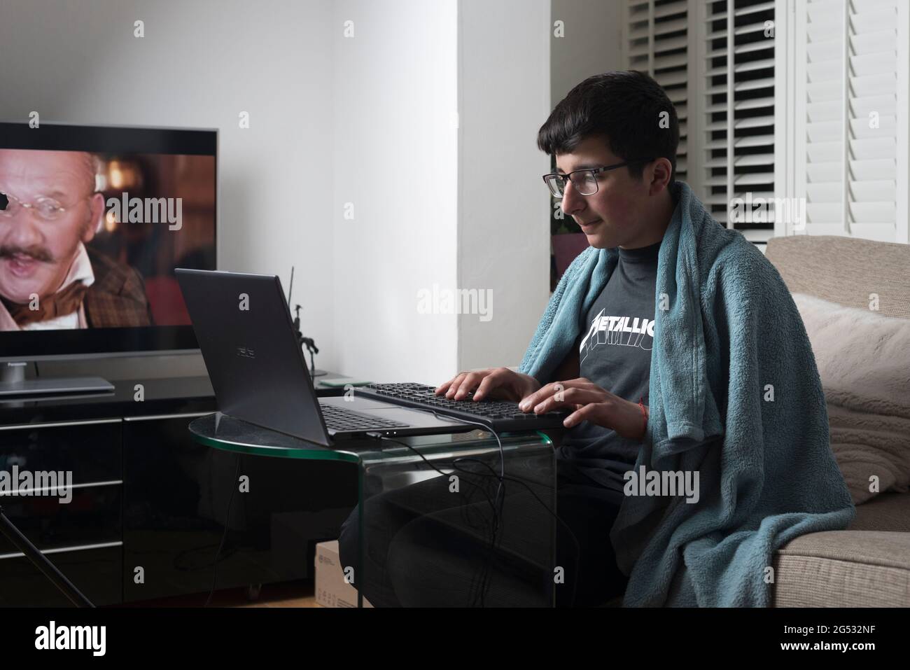 Teenager, Alter 13-14 Jahre, Studie online im Wohnzimmer, Surrey, Großbritannien Stockfoto